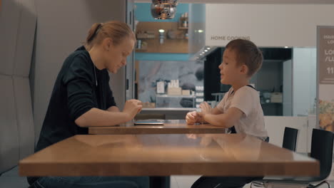 Mom-and-son-in-cafe-browsing-web-on-cell