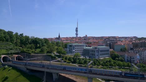 Railroad-Train-leaves-tunnel-over-bridge,-tower