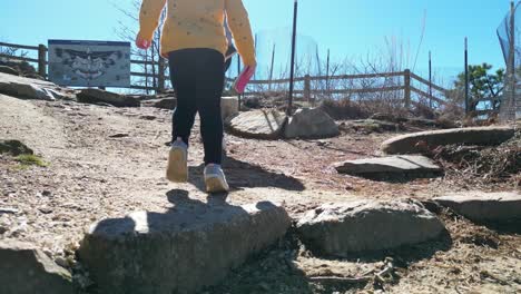 Toddler-walking-behind-mother-up-pilot-mountain-in-mount-airy-North-Carolina