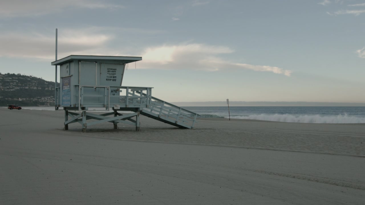 Filmato cinematografico UHD di una torre di salvataggio a Redondo Beach nelle prime ore del mattino. Scena costiera pacifica con luce soffusa, una costa calma, un oceano tranquillo, turismo e uno stile di vita da spiaggia.
