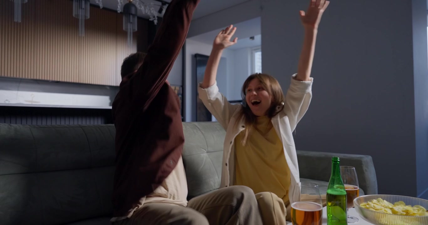 Excited Couple Celebrates Victory While Watching TV at Home