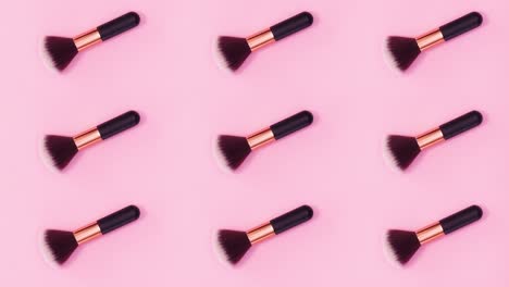 el patrón de concepto de belleza hecho de pinceles de maquillaje se mueve sobre un fondo rosa brillante. detenga el movimiento