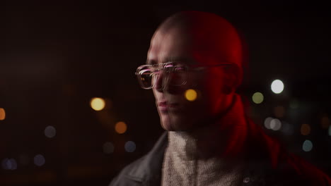moody portrait of a man with glasses and city light reflections at night