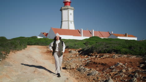 active girl walking lighthouse landscape vertical shot. happy tourist exploring