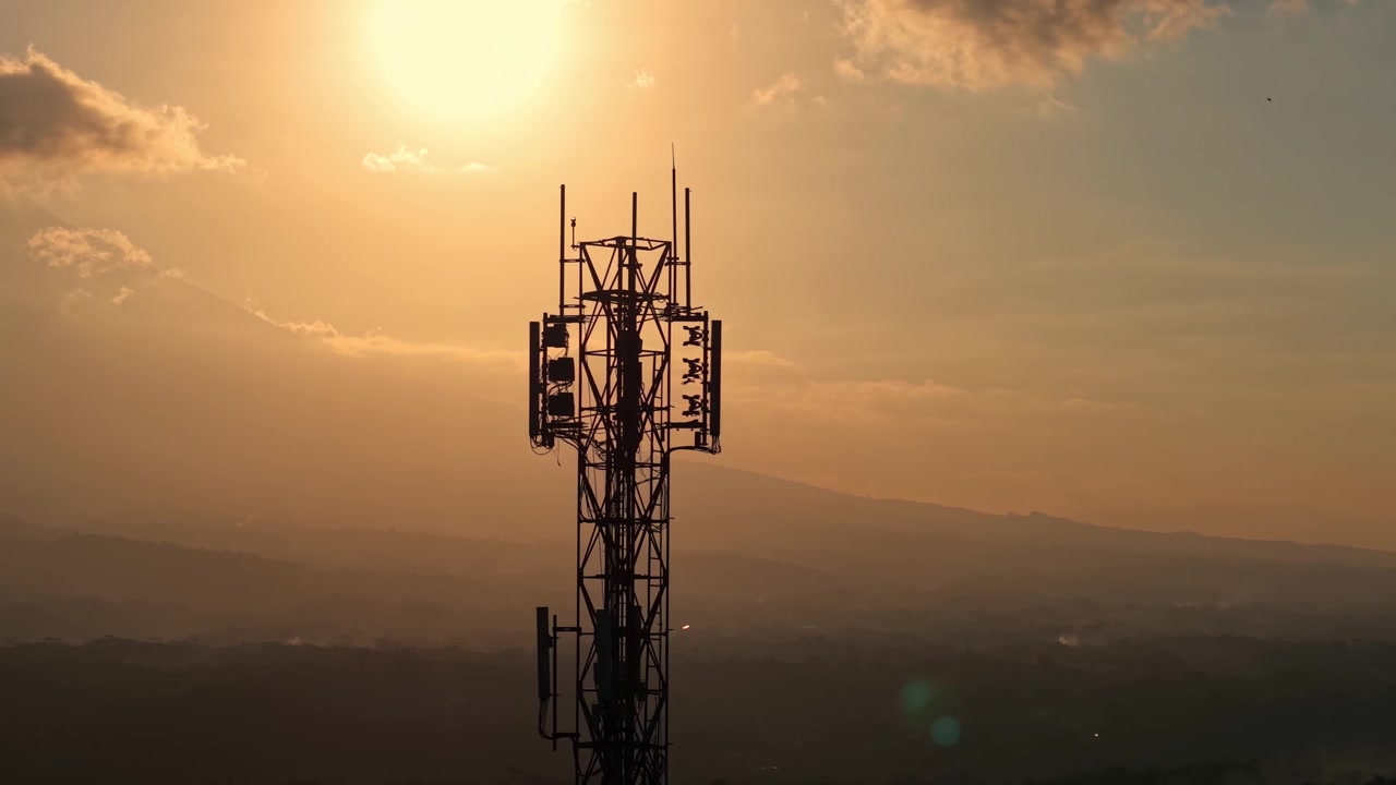 Cell tower silhouette against vibrant sunset sky and clouds. Telecommunication infrastructure, network signal, and technology concept footage.