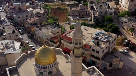 aerial view of a mosque with golden dome and minaret in a middle eastern town