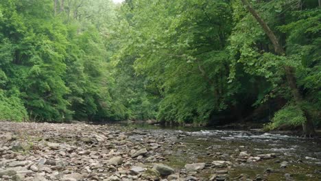 Water-flows-over-stones-at-Wisshaickon-Creek,-trees-in-background