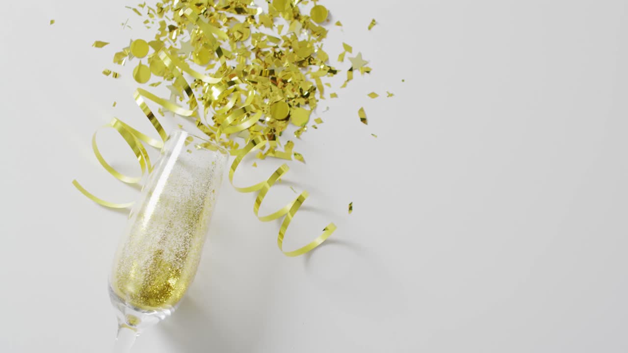 Video di bicchiere di champagne con stelle filanti dorate e coriandoli su bianco, con spazio per il testo