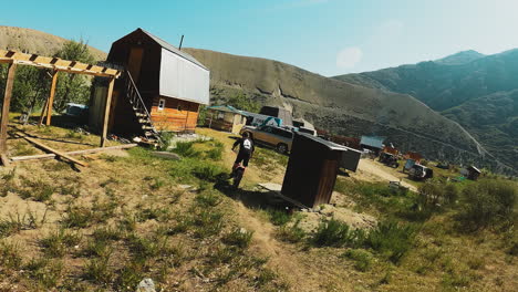 man rides motorcycle at mountain camp fpv. trained sportsman rides standing motorbike along ground road at highland base. extreme sport vehicle