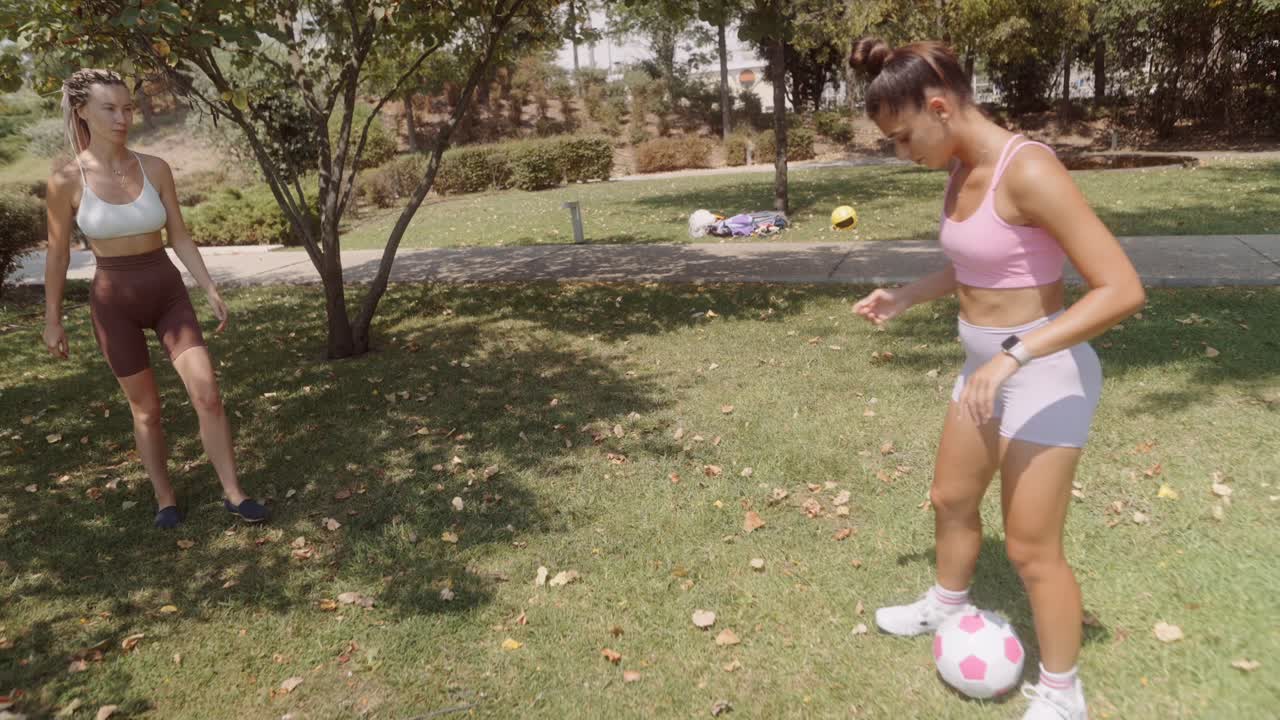 Two women playing soccer in the park