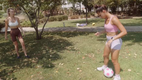 two women playing soccer in the park