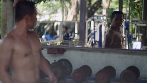 muscular man working out in an outdoor gym looking at his reflection