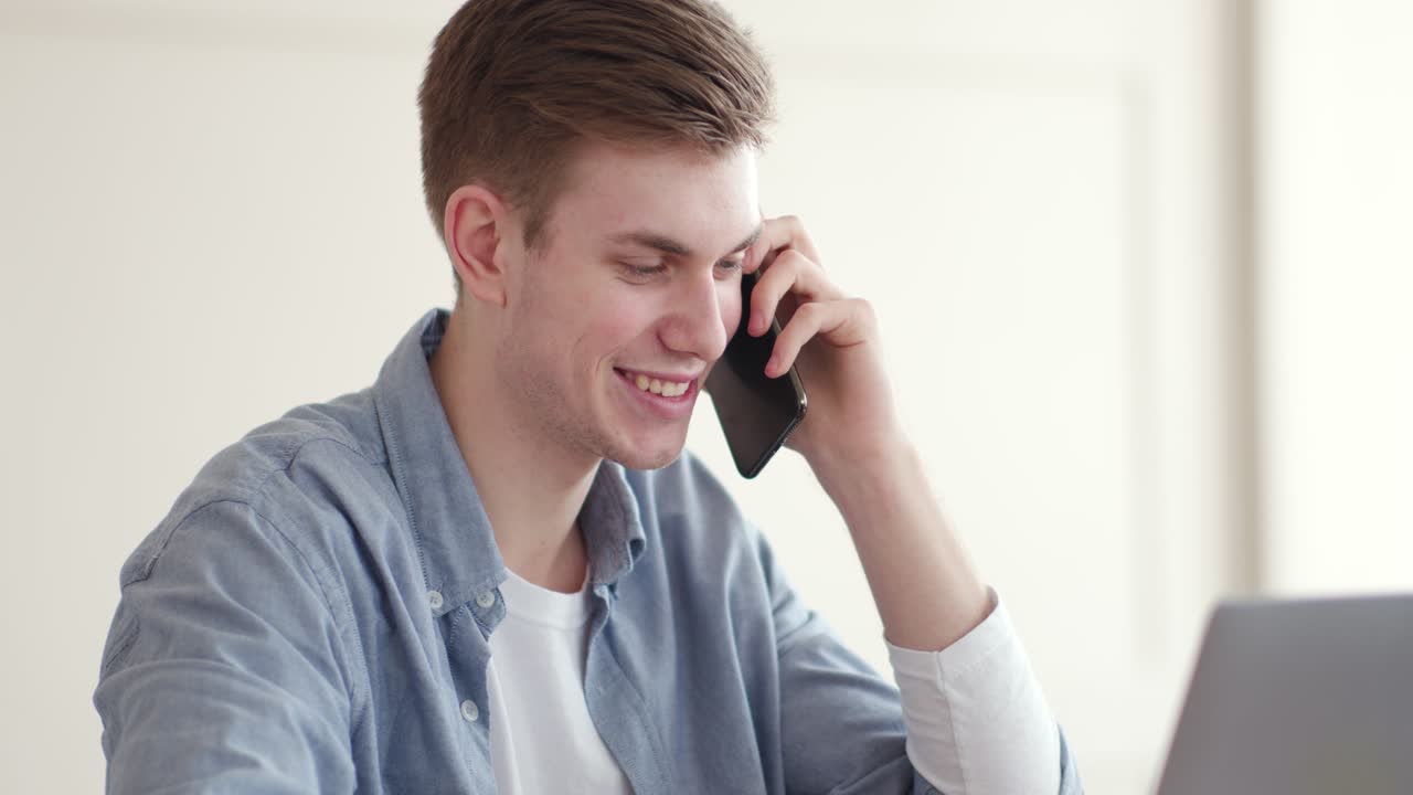Young Man Talking on Phone at Laptop