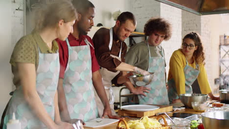 chef putting salad on plate during culinary class with diverse students