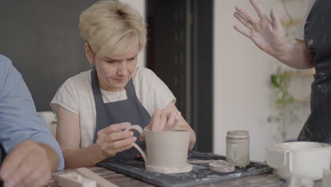 Three-elderly-people-work-on-a-potter's-wheel-in-slow-motion