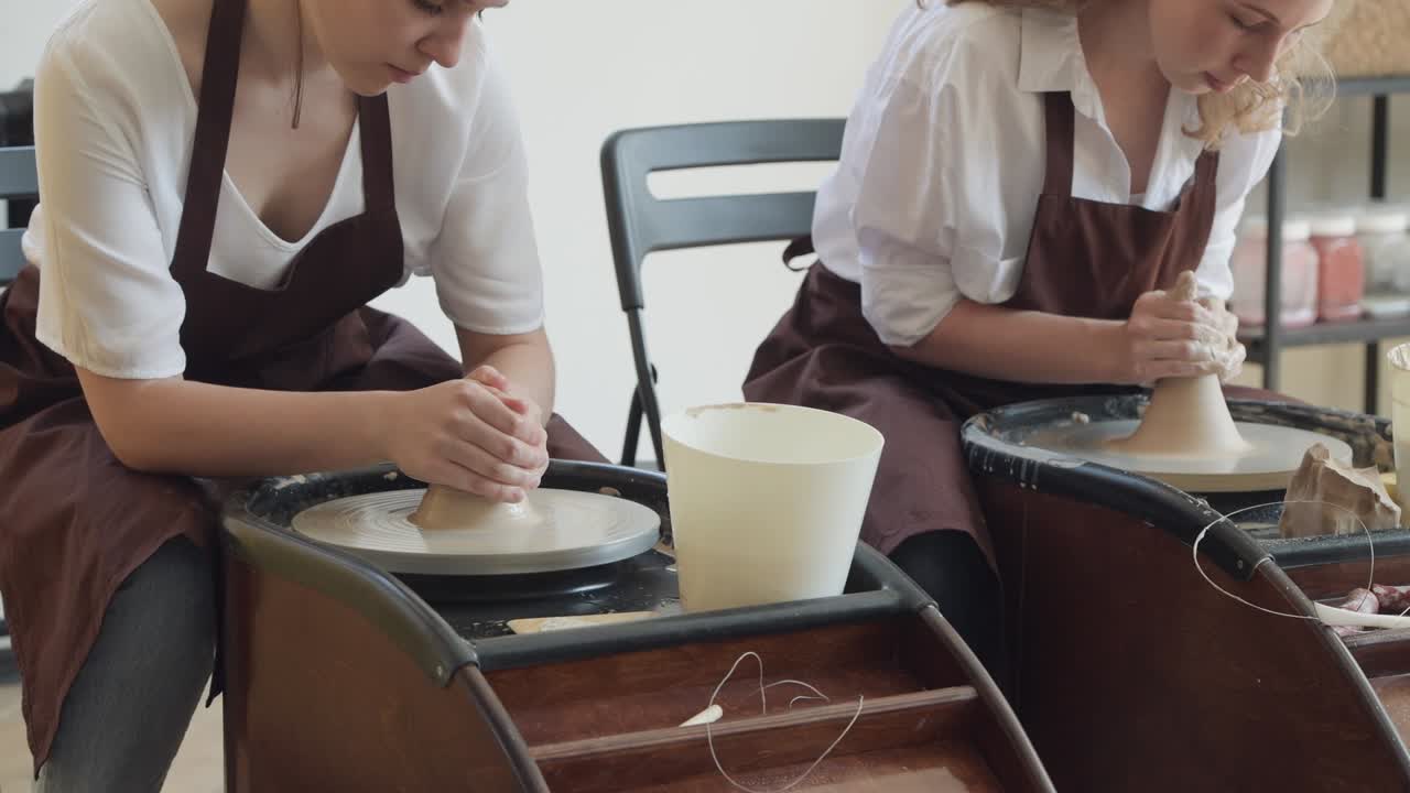 обзор двух молодых гончаков на керамических колесах при подготовке керамических горшков из сырой глины