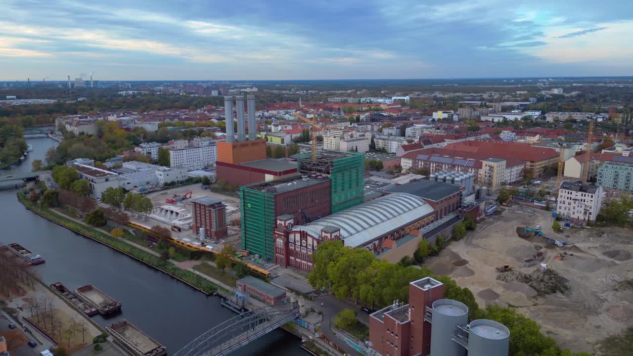 Combined heat and power plant operating in the cityscape by Spree river with new buildings under construction. Unbelievable aerial view flight panorama orbit drone