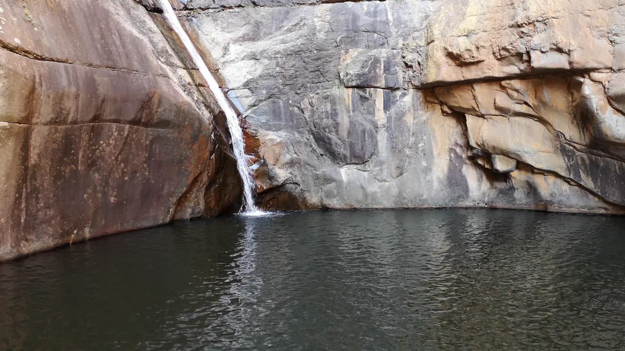 Waterfall in Meiringspoort, Western Cape, South Africa. Narrow stream of clear water falling into cold dark pool