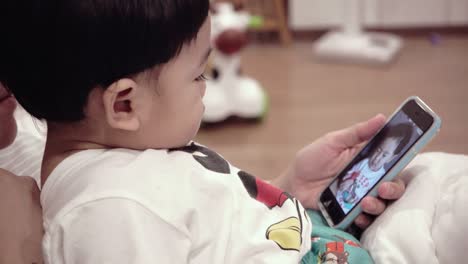 asian baby using mobile phones with mom on the bed