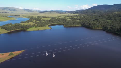 flying above ribnicko lake and gold gondola lift cabins, landscape of zlatibor mountain, serbia