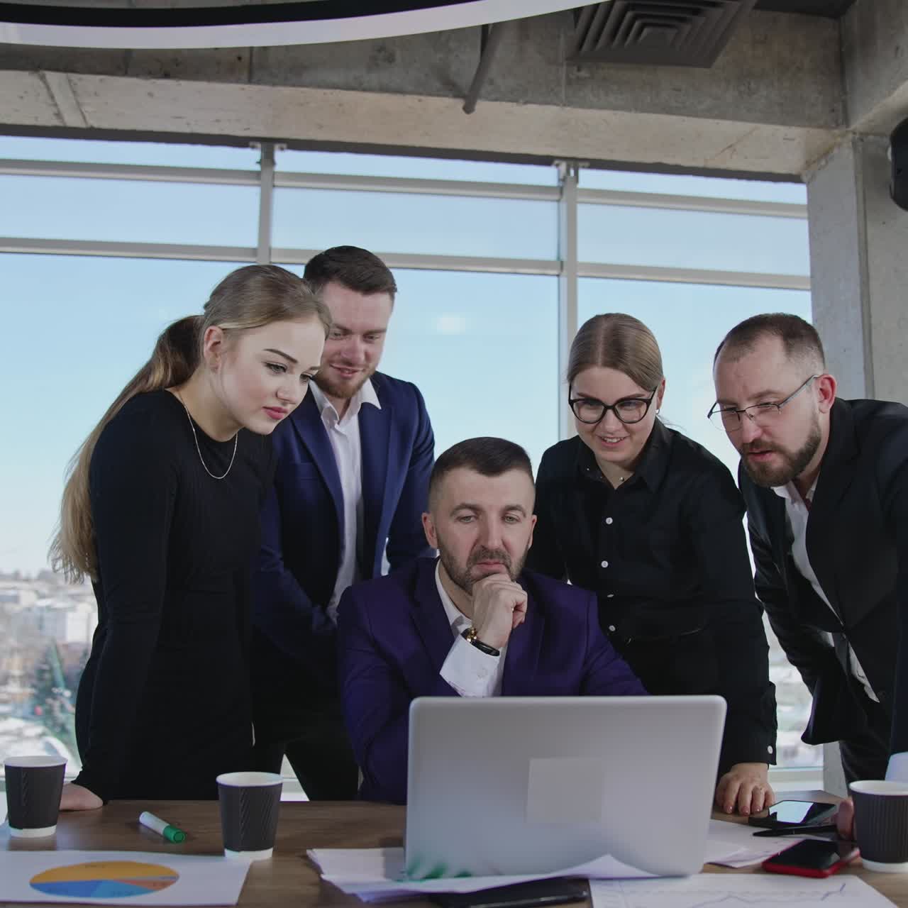 Sharing ideas and finding solutions in teamwork. Business team stand around boss and look at his laptop, talk and smile