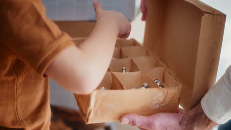 little boy counts christmas baubles in a box and decorates the christmas tree