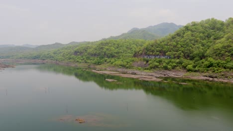 montaña verde con reflejo de agua de río en la mañana desde un ángulo plano