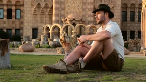 handsome man in cowboy style sits on the grass, with the phone.mosque