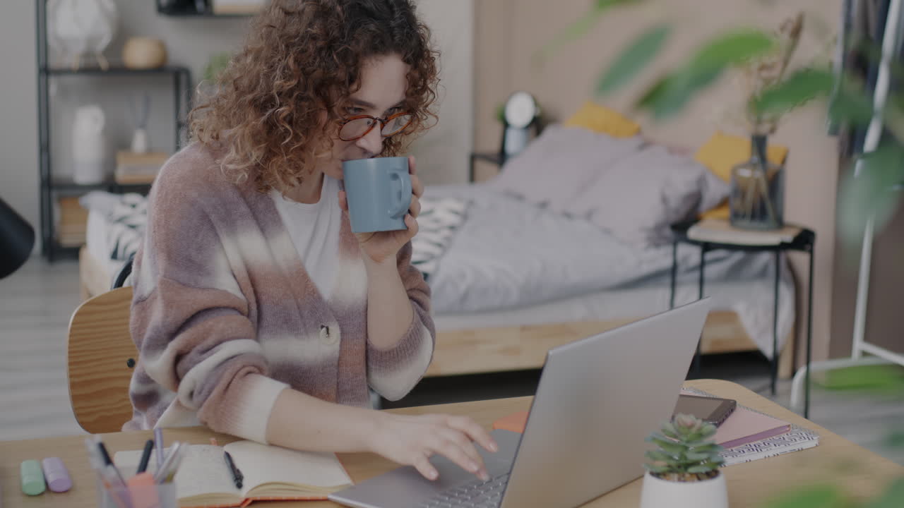 Woman working from home on laptop with coffee