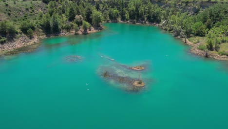 Aerial-shot-overhead-the-vibrant-blue-lake-with-birds-flying-overhead-in-Montpellier,-France