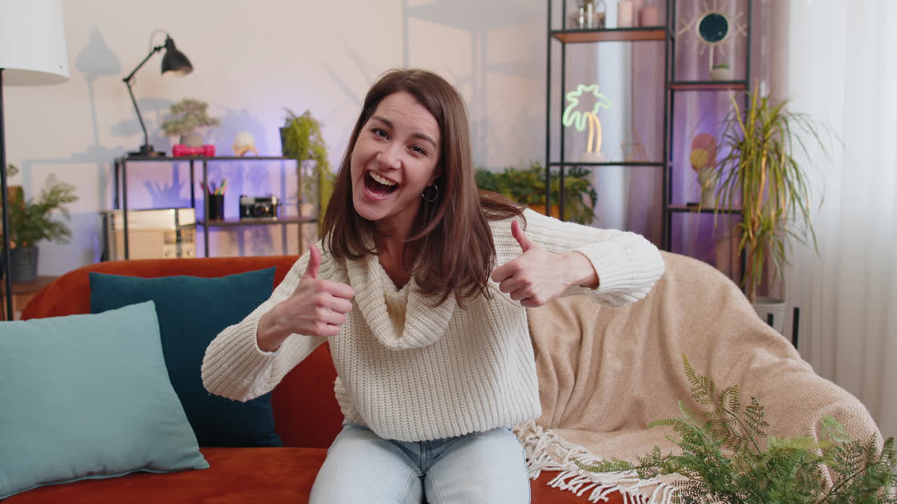 Happy young woman looking approvingly at camera showing thumbs up like positive sign good news