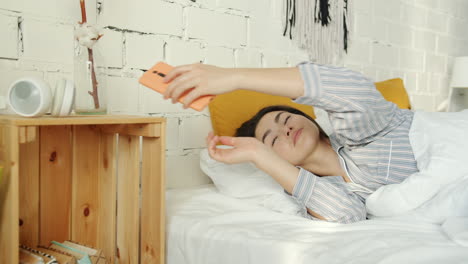 woman checking phone in bed