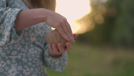 Women&#039;s hands are close-up molded from clay in nature outdoors in the park in the evening at sunset.