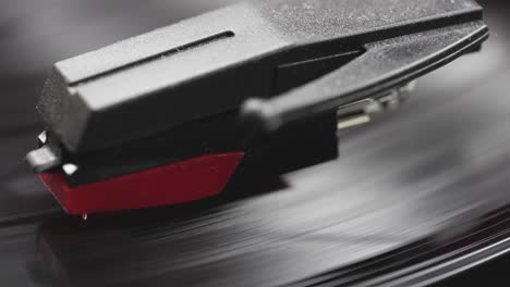 macro view of vintage record player needle reading a grooved melody set on grooved black vinyl