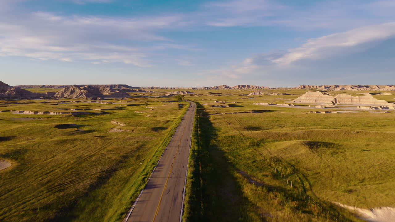 Winding Road Through Rugged Badlands Captured by Drone at Sunset