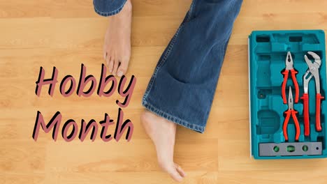 animation of hobby month text over legs woman in jeans sitting on wooden floor with open toolbox