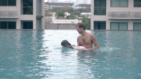 father with children plays in swimming pool slow motion