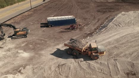 Vogelperspektive-Auf-Eine-Baustelle-Mit-Einem-Vollen-Muldenkipper-Und-Einem-Auslegerlader,-Der-Die-Nächste-Ladung-Vorbereitet