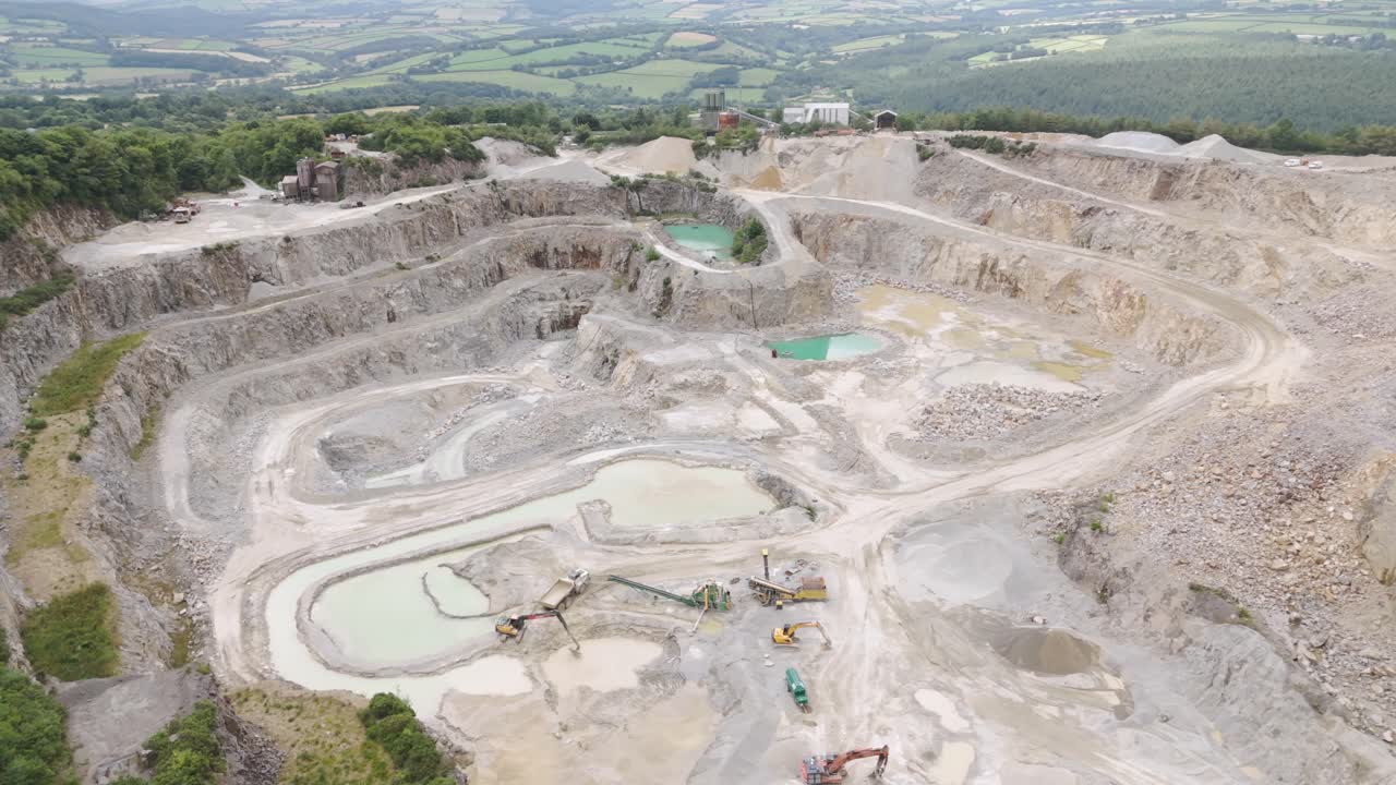 Drone orbital view of an active aggregate quarry mining for material in Cornwall, United Kingdom, with extensive operations and heavy machinery