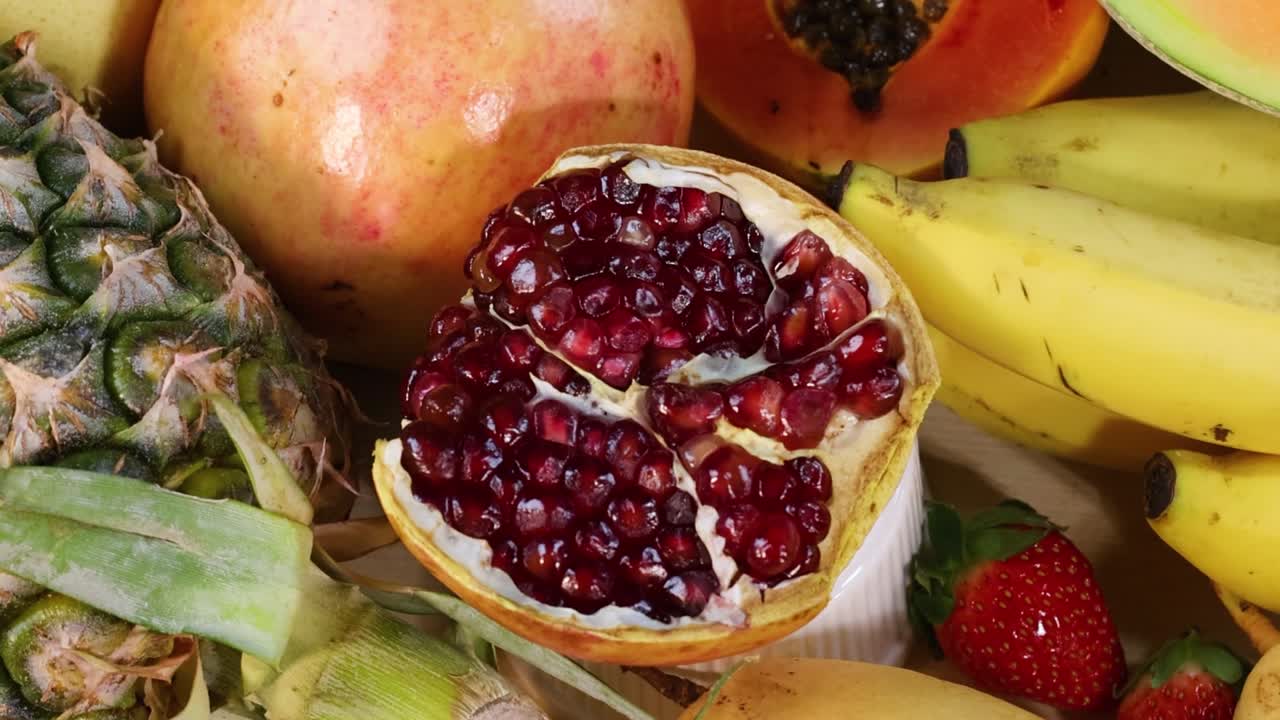 A vibrant display of fresh pomegranate, mango, pineapple, bananas, and strawberries.