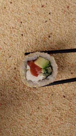 close-up of a california roll held with chopsticks