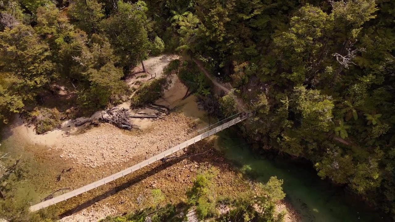 Luftfoto af en hængebro over en turkis flod i Abel Tasman Nationalpark, Sydøen, New Zealand.