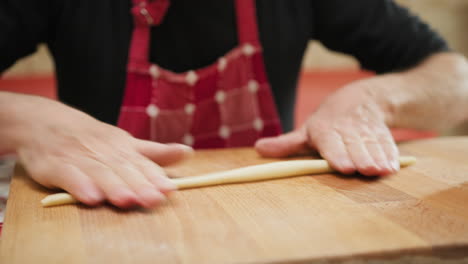 man hands breaking raw dough into small pieces making italian pasta