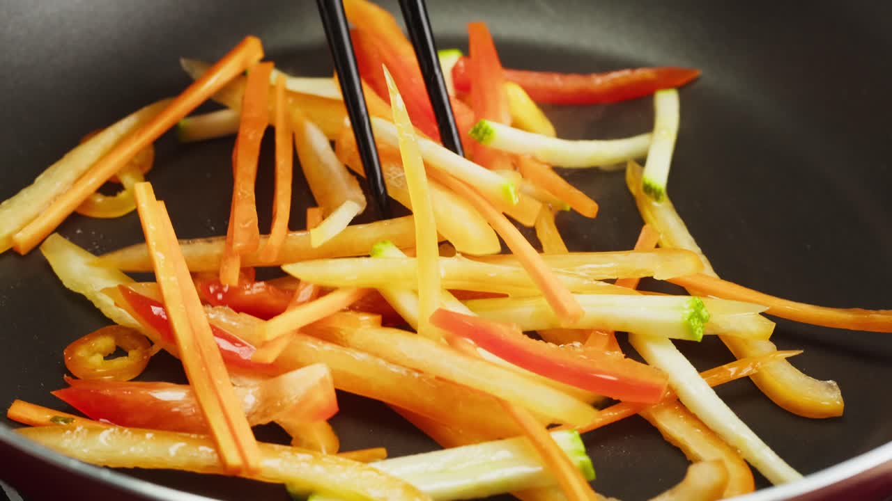 Saltare in padella verdure colorate e affettate in una padella calda