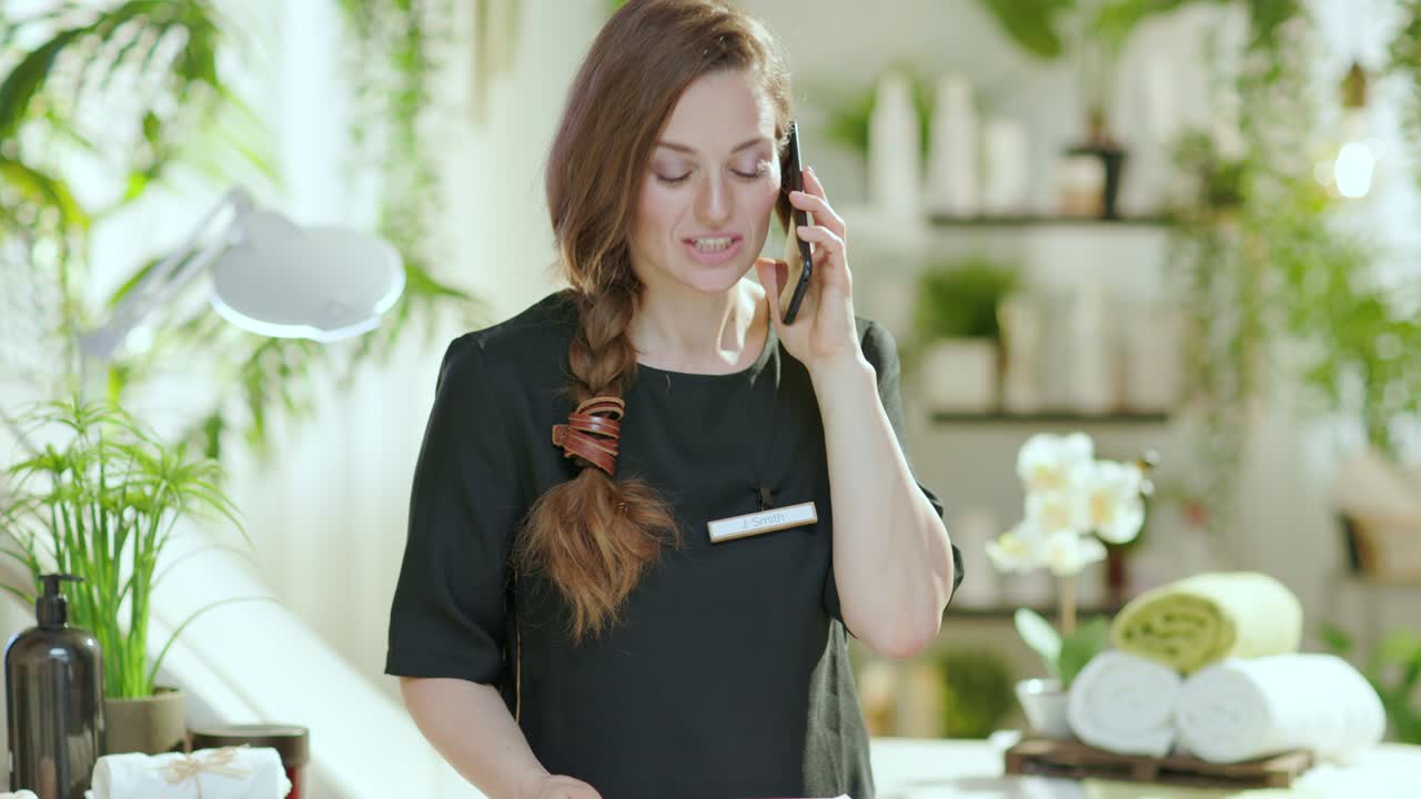 smiling female worker in beauty studio talking on phone