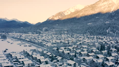 Ciudad-Nevada-De-Garmisch-partenkirchen-Debajo-De-Montañas-Iluminadas-Por-El-Sol,-Disparo-De-Drones