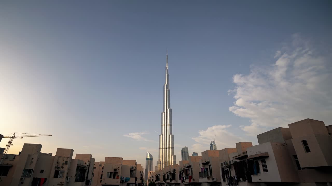 Burj Khalifa towering over Dubai's skyline, surrounded by residential buildings and illuminated by the warm glow of sunset, highlights the contrast of modern architecture and urban life