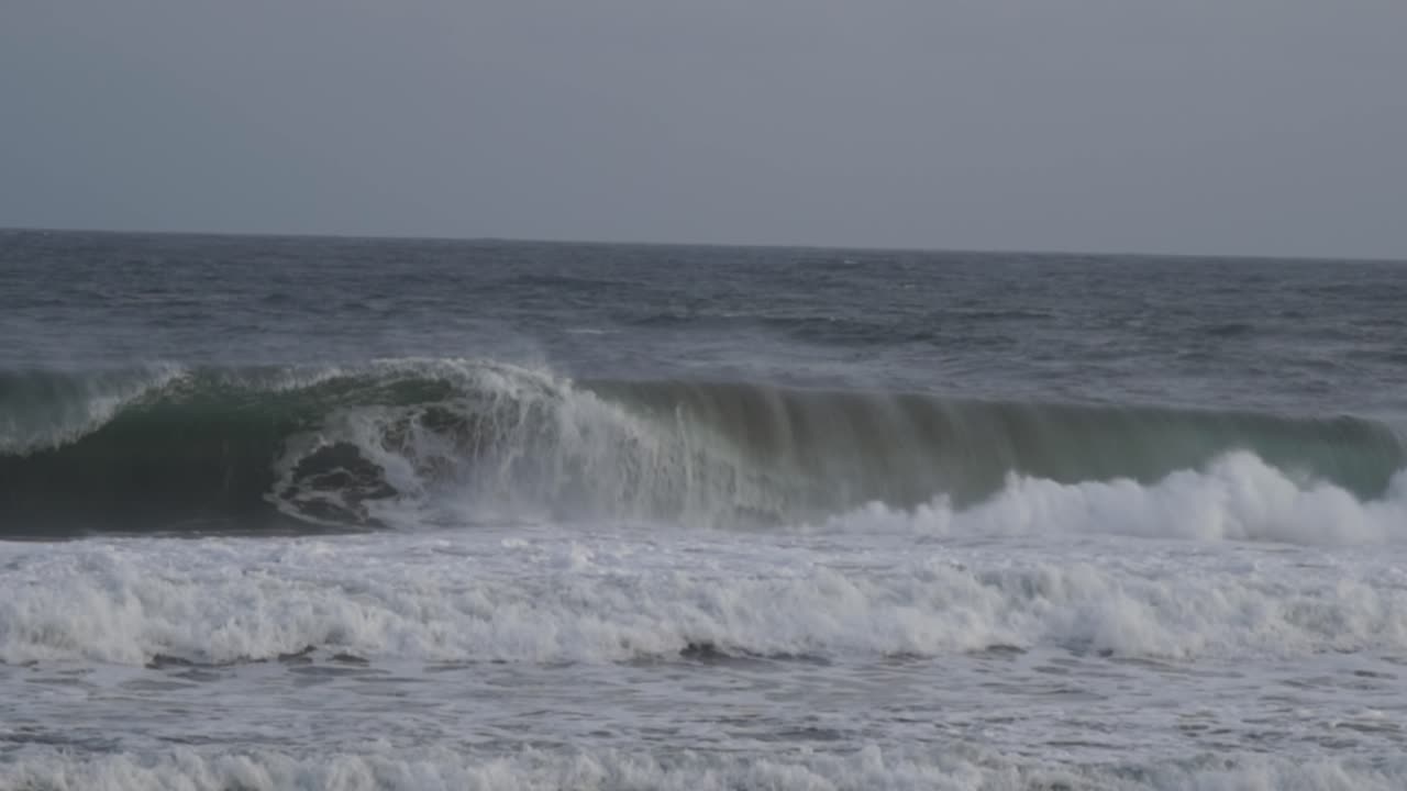강력한 해안 파도가 빈 공허한 배럴에 부히며 폭풍우가 불어오는 해변에서 화이트으로 터져 나옵니다.