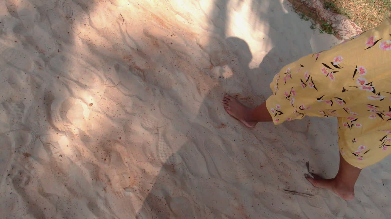 Camminata a piedi nudi su spiaggia soleggiata presso un resort a Goa, al rallentatore.