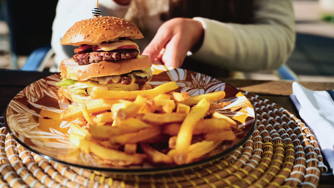 Close up of a gourmet cheeseburger and crispy French fries served on a decorative plate